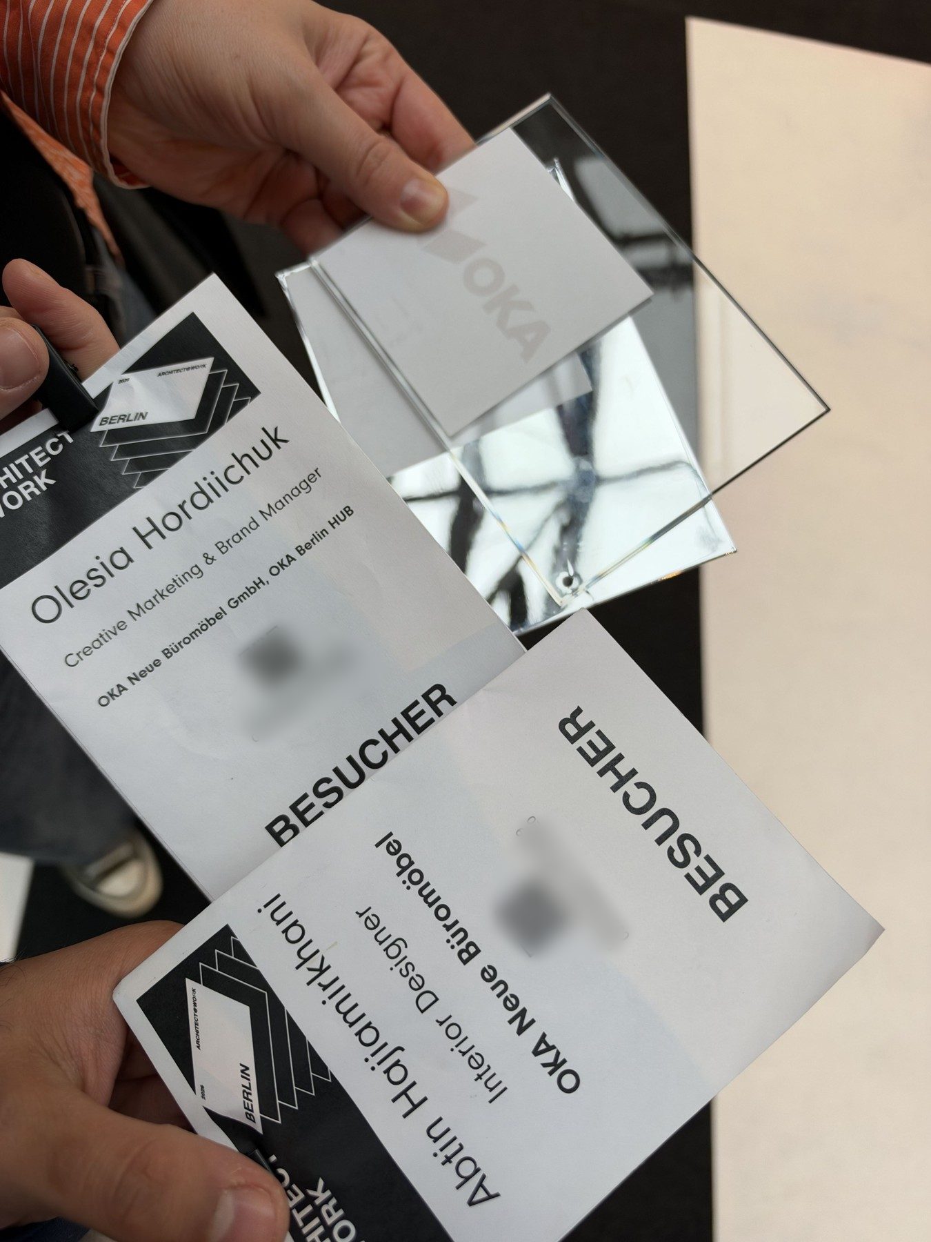 Die Besucherausweise von Olesia Hordiichuk und Abtin Hajiamirkhani mit einem OKA-Schild aus Acrylglas